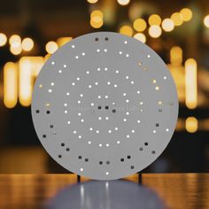 a round metal object sitting on top of a wooden table with lights in the background