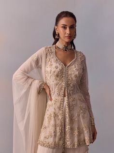 Dazzle in the elegance of the Mariam gharara set, featuring a regal ethnic design adorned with intricate hand embroidery on the jacket, enhanced with beads and sequins. Paired with a layered sharara and a coordinated dupatta, this ensemble creates a stylish look perfect for festive celebrations and wedding occasions. Beige Set With Intricate Embroidery And Traditional Drape, Beige Sets With Intricate Embroidery For Designer Wear, Cream Georgette Sharara For Reception, Chinon Palazzo Set With Intricate Embroidery And Long Sleeve, Sharara With Intricate Embroidery For Reception, Festive Off-white Georgette Sharara, Beige Palazzo Set With Resham Embroidery For Reception, Cream Sets With Resham Embroidery For Reception, Beige Floor-length Sets With Intricate Embroidery