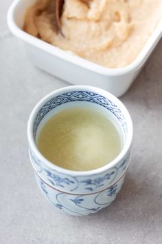 a bowl of hummus with a spoon in it next to a container of hummus