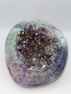 a purple and green object on a white surface with lots of small crystals in it