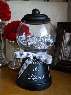 a glass bowl with some candy in it on top of a table next to flowers