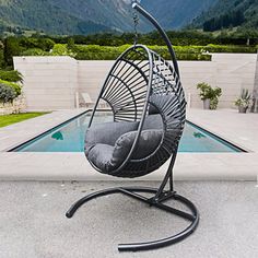 a hanging chair next to a pool with mountains in the background