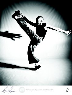 black and white photograph of a man doing a dance move with his arms stretched out