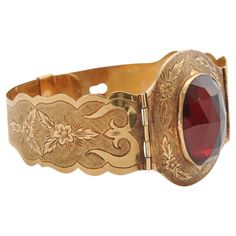 This antique bracelet is a stunning example of fine craftsmanship from a bygone era, likely dating from the late 19th to early 20th century. The bracelet is crafted from 14 karat gold, known for its durability and warm, rich color, which has developed a subtle patina over time. The centerpiece of the bracelet is a large, oval-shaped garnet, expertly cut in the rose-cut style. This cut, characterized by its flat base and domed, faceted top, is designed to maximize the stone's brilliance and depth of color. The garnet is a deep, rich red with flashes of lighter hues that catch the light beautifully, adding a touch of vibrant color to the piece. Garnets were popular gemstones in antique jewelry, often associated with love, passion, and protection. The bracelet features two hinged sections tha Luxury Victorian Engraved Cuff Bracelet, Luxury Antique Engraved Cuff Bracelet, Engraved Bangle Bracelet, Engraved Bangle, Almandine Garnet, Yellow Gold Bangle, Antique Bracelets, Victorian Gold, Gold Engraving