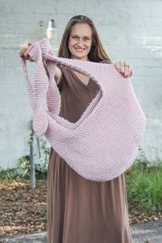 a woman holding up a pink crocheted bag