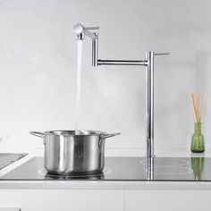 a large pot on top of a stove next to a faucet with water running from it