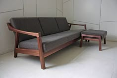 a gray couch sitting next to a wooden table on top of a white tile floor