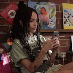 a woman with dreadlocks is looking at her cell phone while sitting on a couch