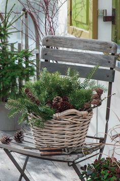 a wooden chair sitting on top of a porch next to potted plants and pine cones