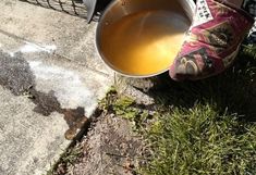 a person is pouring water into a metal bucket on the side of the road,