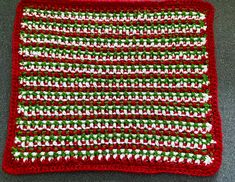 a red and white crocheted dishcloth on a gray surface with green trim