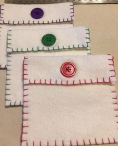 three pieces of white fabric with red and green buttons on them, sitting next to a ruler