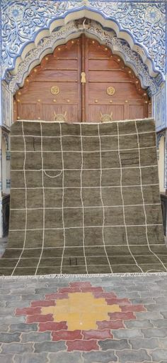 the entrance to an old building with a large rug on it's floor and two wooden doors