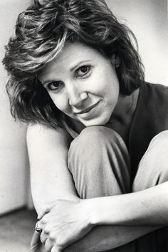 a black and white photo of a woman with her hands on her knees looking at the camera