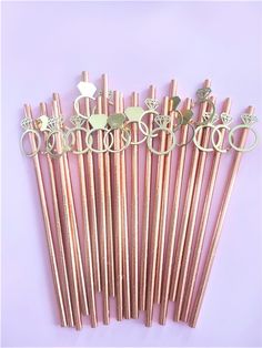 several different types of metal straws on a purple background with the word love spelled in gold