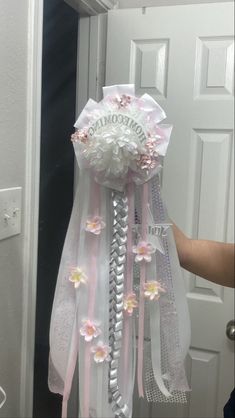 someone is holding up a hair comb decorated with flowers and ribbons in front of a door