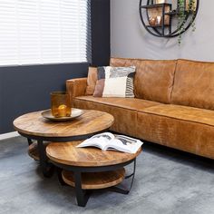 a brown leather couch sitting in a living room next to a wooden table with a magazine on it