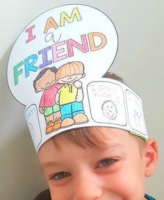 a young boy wearing a paper hat with the words i am a friend written on it