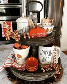 a cake stand with pumpkins and coffee mugs sitting on it's sides