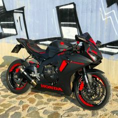 a red and black motorcycle parked in front of a wall