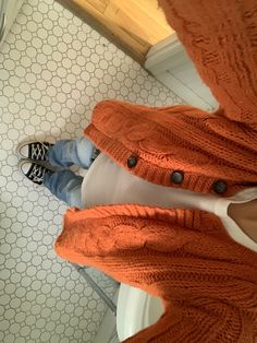 a person standing in front of a mirror wearing an orange sweater