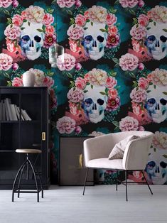 a room with a chair, bookcase and wallpaper that has a floral skull on it