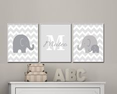 three gray and white wall art prints featuring elephants, chevroned background with the letter m