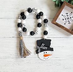 a snowman ornament and some decorations on a white wooden table with a frame