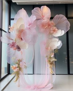 an arrangement of balloons and flowers in front of a window