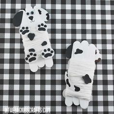 two dogs made out of toilet paper sitting on a checkered tablecloth with black and white gingham