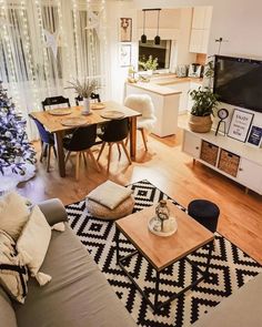 a living room filled with furniture and a christmas tree in front of a tv mounted on the wall