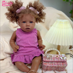 a doll sitting on a bed next to a purse