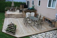 a wooden deck with chairs and table next to a house