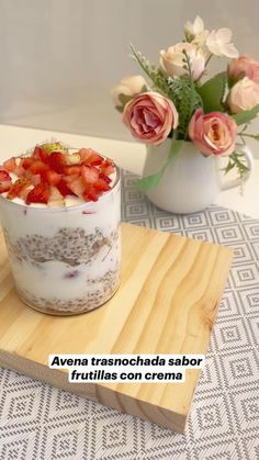 there is a dessert with strawberries in it on the wooden tray next to flowers