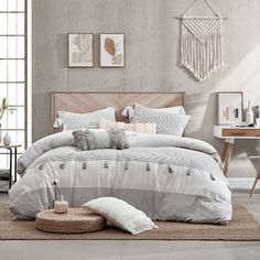 a bed with white and grey comforters in a room