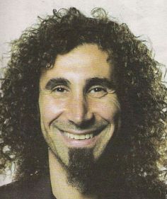 a man with long curly hair smiling at the camera