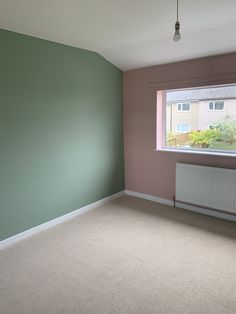 an empty room with a radiator in the corner and a window on the far wall