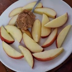 an apple slices and peanut butter on a white plate with a spoon in the middle