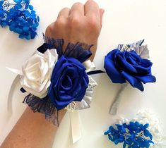 two wrist corsages with blue and white flowers on them, one being tied to the wrist