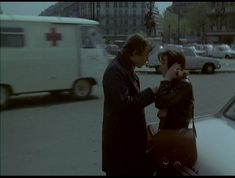 a man talking on the phone next to a woman in a black coat and brown purse