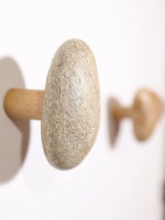 a close up of a rock on a wooden handle with a white wall in the background