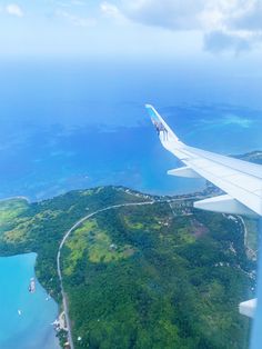 an airplane wing flying over the ocean and land