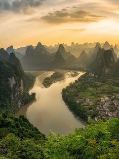 an aerial view of a river surrounded by mountains and greenery in the foreground