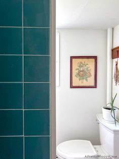 a white toilet sitting next to a green tiled wall