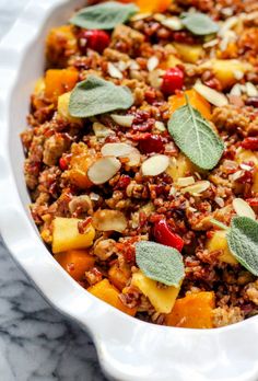 a casserole dish filled with fruit, nuts and sage leaf garnish