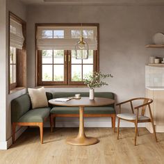 a corner table with two chairs and a bench in front of a window that overlooks a kitchen