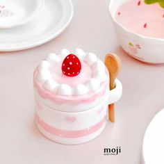 a pink and white cake with a strawberry on top sitting in front of two bowls