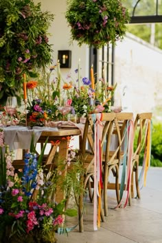 the table is set with flowers and candles for an outdoor dinner or party, along with ribbons tied around it