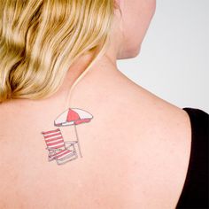 the back of a woman's shoulder with an umbrella and chair tattoo on it