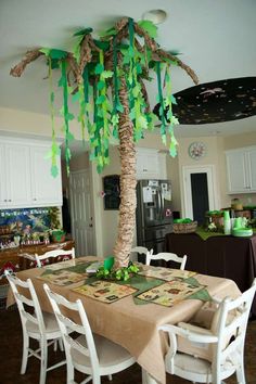 a palm tree is decorated with green streamers and paper decorations on the table top